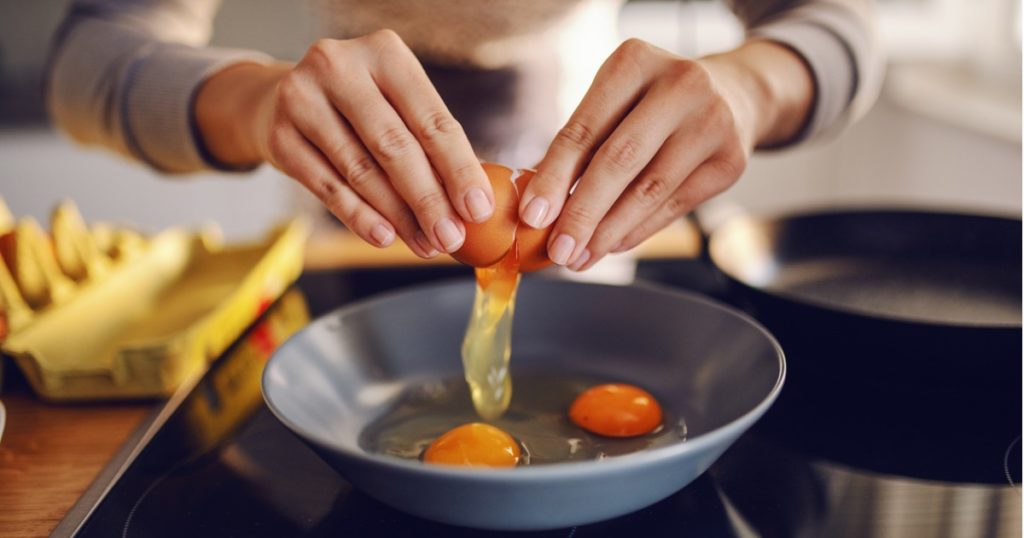 特写手破解一个鸡蛋放到锅里的炉子。